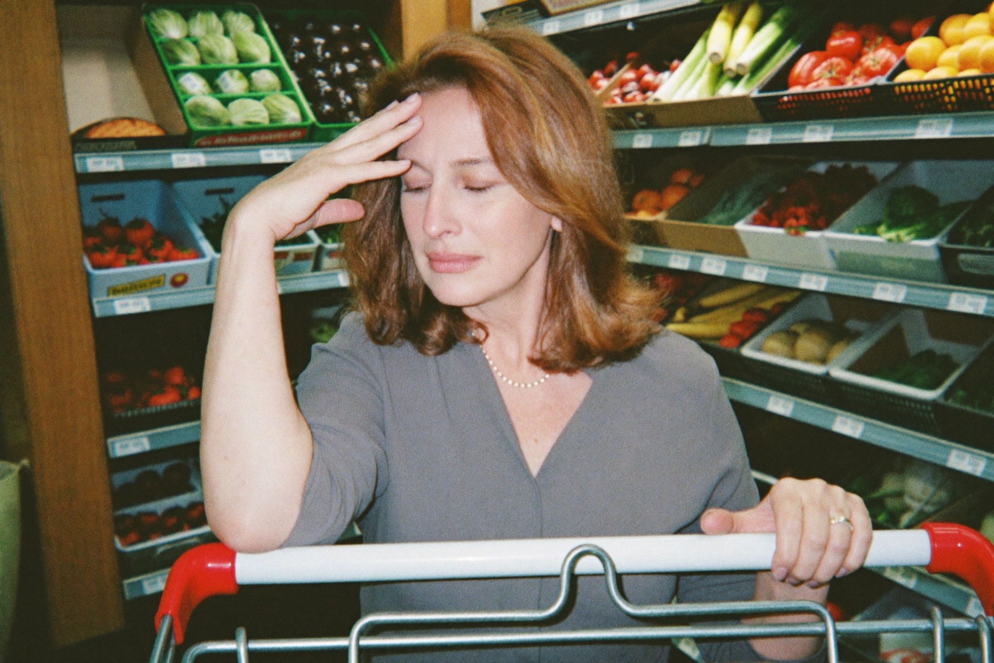 Woman steadying herself on a shopping cart in a grocery aisle